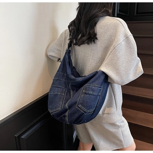 Detail of large navy denim hobo bag featuring contrast stitching and large pockets