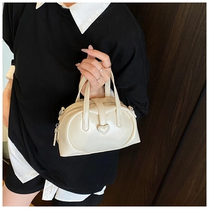 Detail of a creamy white pearlized mini pillow bag featuring a 3D heart decoration