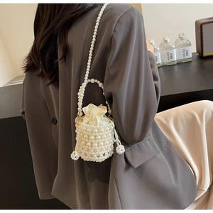 Detail of a pearl-woven bucket bag with cream satin drawstring lining and handheld strap