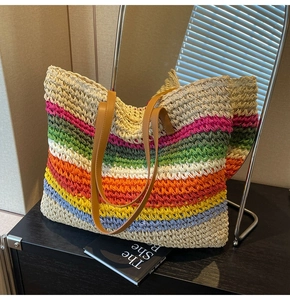 Close-up of rainbow woven straw tote bag with brown faux leather handles on black wood
