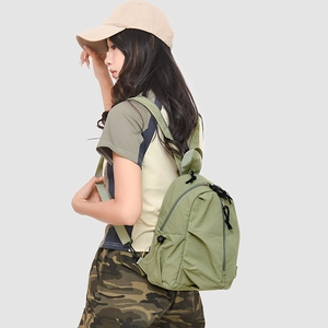 Détail du mini sac à dos en nylon vert clair montrant la texture et la poche latérale