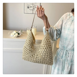 Detail of hand-woven straw tote bag with intricate floral patterns and brown leather strap