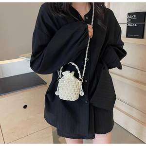 Detail of woven pearl bucket bag with white satin drawstring liner and chain strap