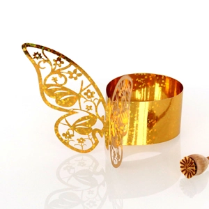Close-up of golden laser-cut butterfly napkin ring with glitter finish and mirror reflection