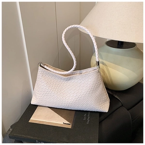 Détail de la texture tissée blanche et des finitions argentées sur un sac baguette