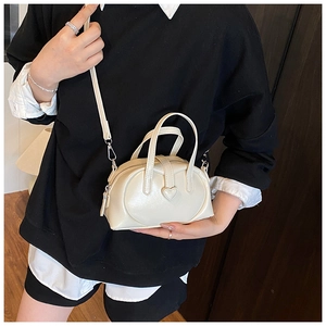 Chic cream white PU leather pillow bag with heart buckle shown on a female model