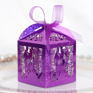 Detail of purple laser-cut wedding favor box with glitter finish and Mr & Mrs heart pattern