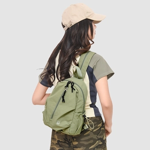 Détail du sac à dos en nylon vert avec poche zippée diagonale et poches latérales à cordon