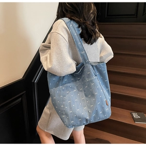 Blue denim tote bag with white bow pattern shown on model in casual daily setting