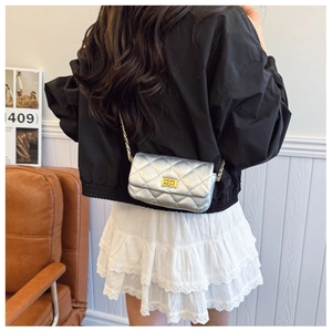 Détail d'un mini sac bandoulière argenté matelassé avec fermoir doré et bandoulière chaîne