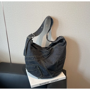 Detail of black washed denim hobo bag featuring contrast yellow stitching and utility pockets