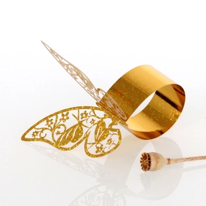 Detailed close-up of golden hollow butterfly napkin ring with laser-cut floral wings