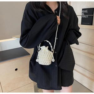 Detailed view of hand-woven pearl bucket bag with drawstring satin lining and flower charm