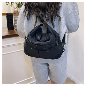 Detailed view of the multi-pocket black crossbody bag showing its durable nylon fabric