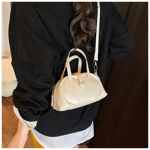Chic beige pillow bag with heart detail worn as a crossbody purse in a cozy home setting