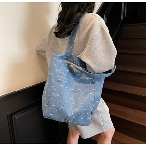 Blue denim tote bag detail featuring white heart and bow patterns with wide strap