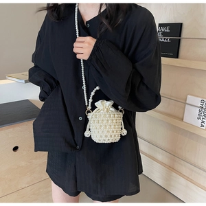 Detail of white pearl woven bucket bag with satin drawstring liner and long pearl chain