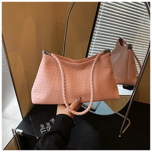 Détail du sac à bandoulière rose tissé avec boucle en métal et design trapézoïdal