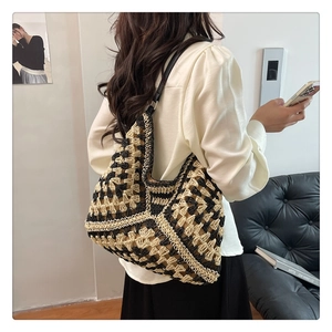 Close-up of a woven hobo bag with black and beige geometric patterns on a model's shoulder