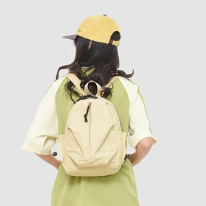 Modèle portant un sac à dos en nylon crème avec poches latérales à cordon réglable