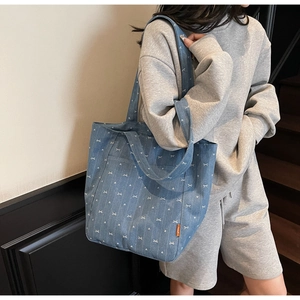 Blue denim tote bag detail featuring white bow and heart patterns with orange side label