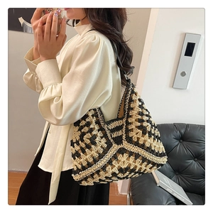 Detail of hand-woven geometric hollow pattern on a large black and beige knit tote bag