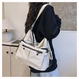 Detail of off-white multi-pocket tote bag showing nylon texture and adjustable strap