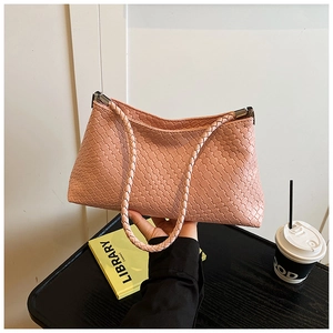 Détail de la texture du cuir tressé sur le sac rose clair avec motif géométrique
