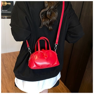 Detail of red heart-shaped mini crossbody bag with sleek synthetic leather and thin strap