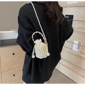 Detail of beaded mini pearl bucket bag with silk drawstring lining and elegant cross-body strap