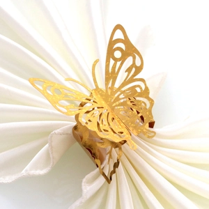Elegant gold butterfly napkin ring with laser-cut hollow design on white folded napkin