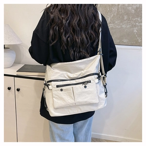 Detail of white nylon messenger bag with multi-zipper pockets on back of a model
