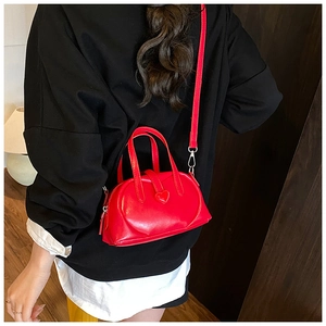 Detail of red heart-shaped leather mini handbag showing glossy texture and side profile