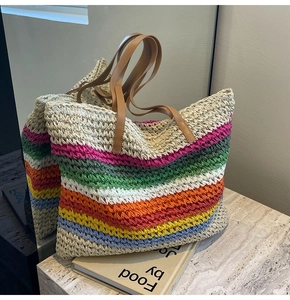 Close-up of vibrant rainbow striped woven straw tote bag with brown leather straps