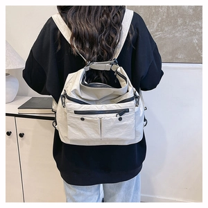 Detail of white nylon tote bag with multiple pockets and adjustable black straps