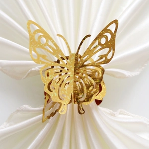 Golden laser-cut butterfly napkin ring with glitter finish on white silk background