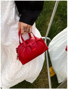 Detail of red heart-shaped mini pillow bag with smooth faux leather texture and dual handles