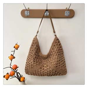 Detailed close-up of a woven hollow-out straw hobo bag with a matching leather shoulder strap