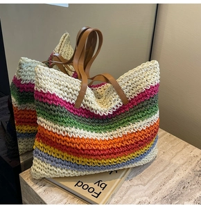 Detail of hand-woven rainbow crochet tote bag with brown leather handles on marble