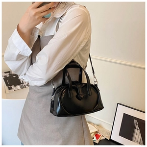 Detail of a black patent leather Boston bag with a heart-shaped clasp and twin handles