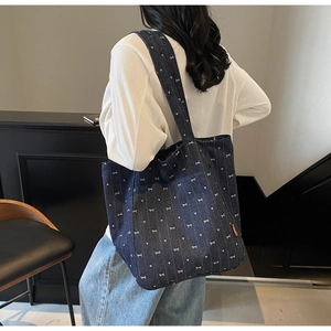 Detail of blue denim tote bag featuring white bow patterns and large capacity for women