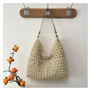 Detailed close-up of beige woven tote bag with brown leather straps on a wooden hook