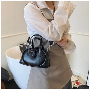 Detail of a black glossy PU leather handbag with a 3D heart motif and silver hardware