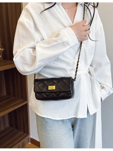 Sac bandoulière matelassé noir avec chaîne dorée porté par un mannequin femme