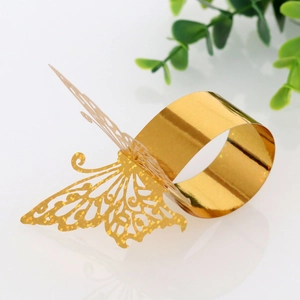 Macro shot of glittery gold laser-cut butterfly napkin ring on a reflective white surface