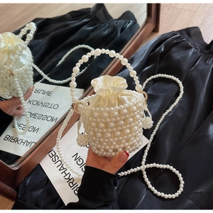 Detail of woven faux pearl bucket bag with satin drawstring liner on silk background