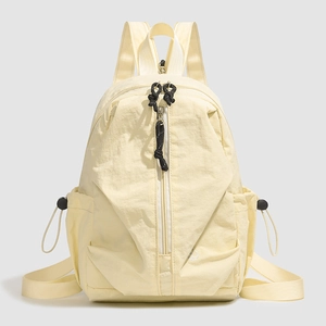 Détail du sac à dos en nylon beige avec fermeture éclair verticale et poches latérales à cordon