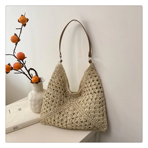 Detail of beige crochet tote bag featuring geometric knit patterns and a brown leather strap