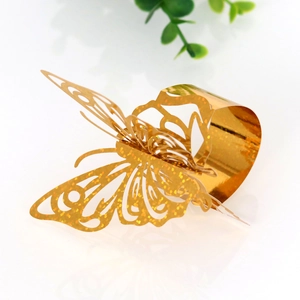 Macro shot of gold butterfly napkin ring featuring laser-cut hollow pattern and glitter finish