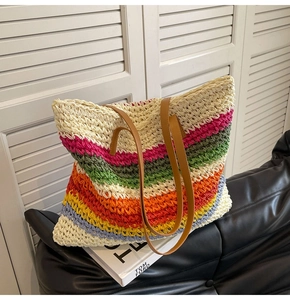 Detail of colorful woven rainbow straw tote bag with brown leather shoulder straps